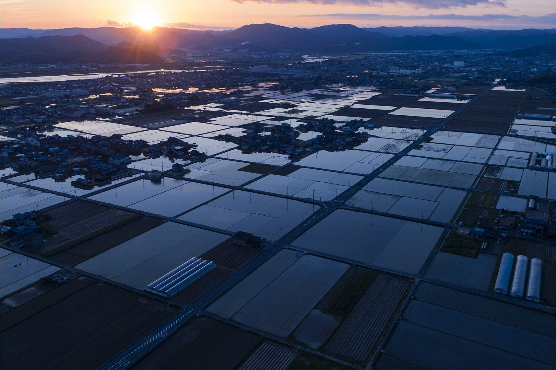 水田群と夕日の空撮写真
